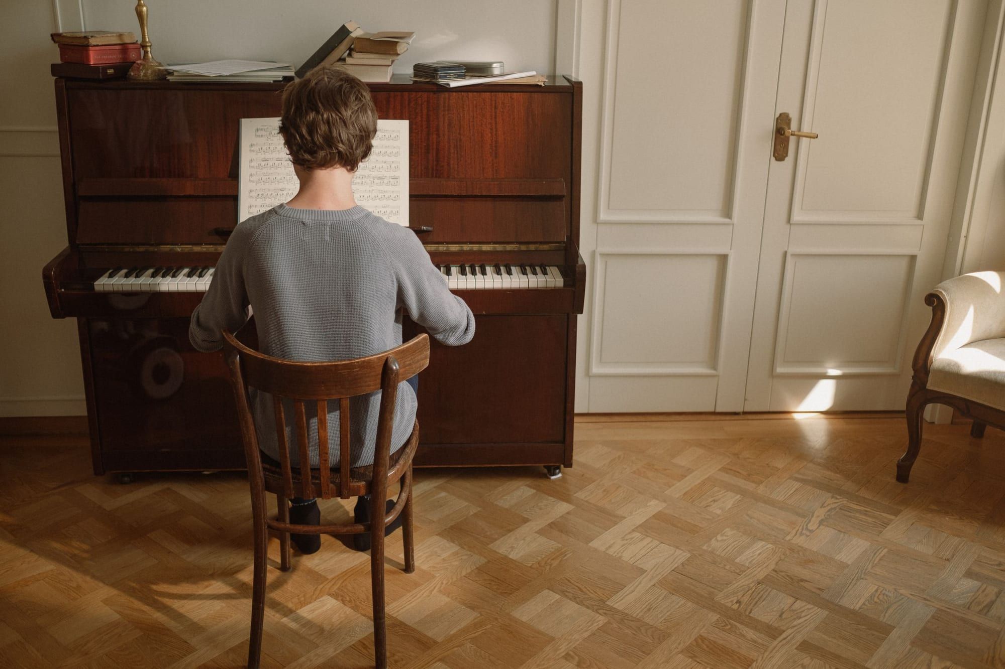 Person som spelar på ett mörkt piano i ett rum med parkettgolv